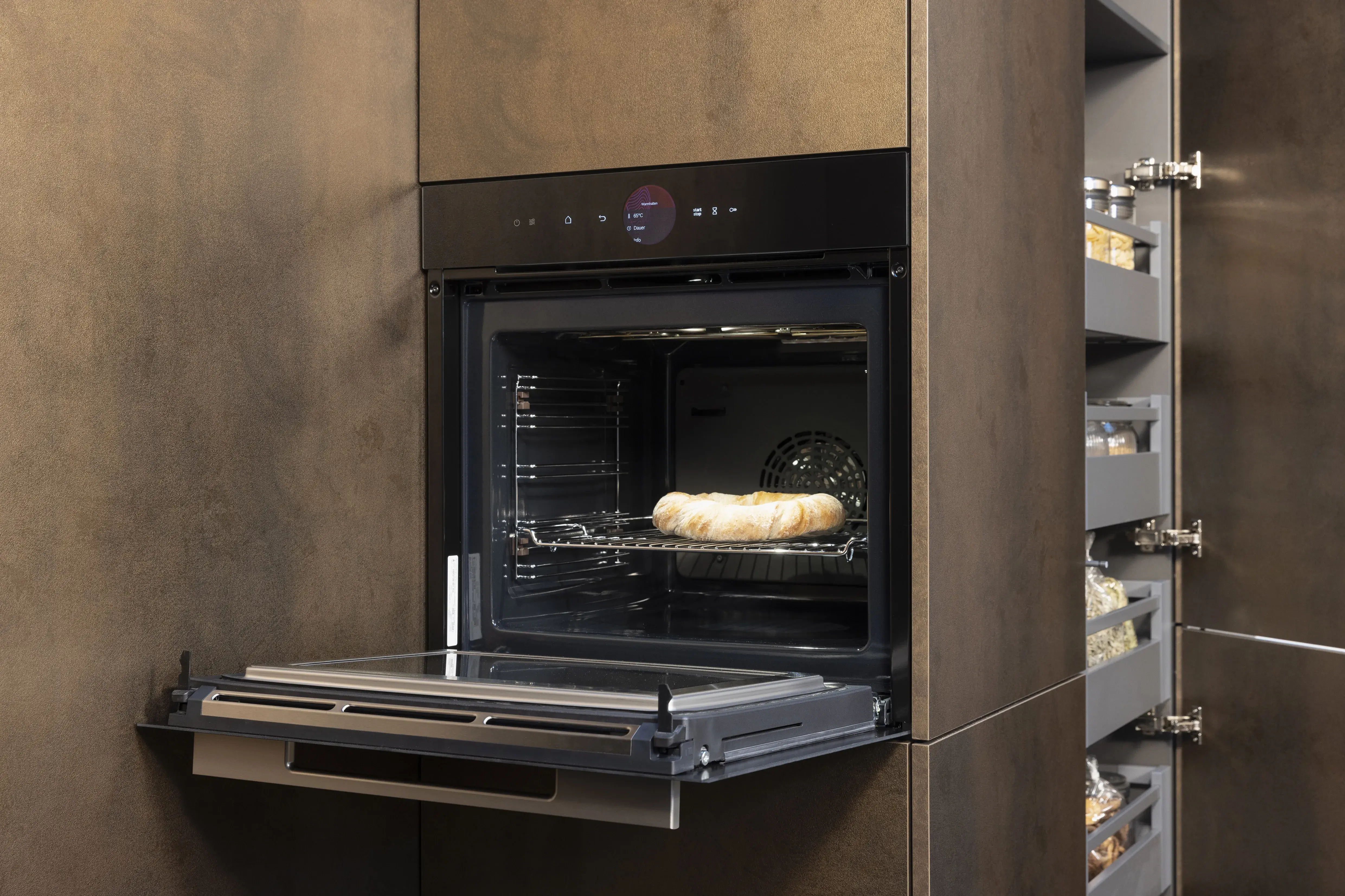 Kuchen im modernen, geöffneten Einbau-Backofen in einer braunen Küchenzeile